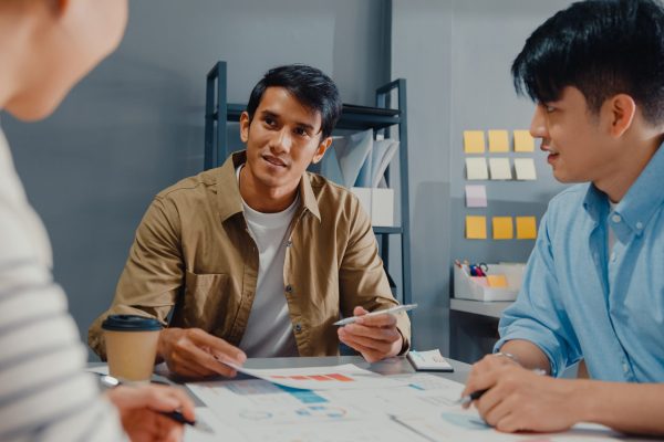 Happy young Asia businessmen and businesswomen meeting brainstorming some new ideas about project to his partner working together planning success strategy enjoy teamwork in small modern home office.